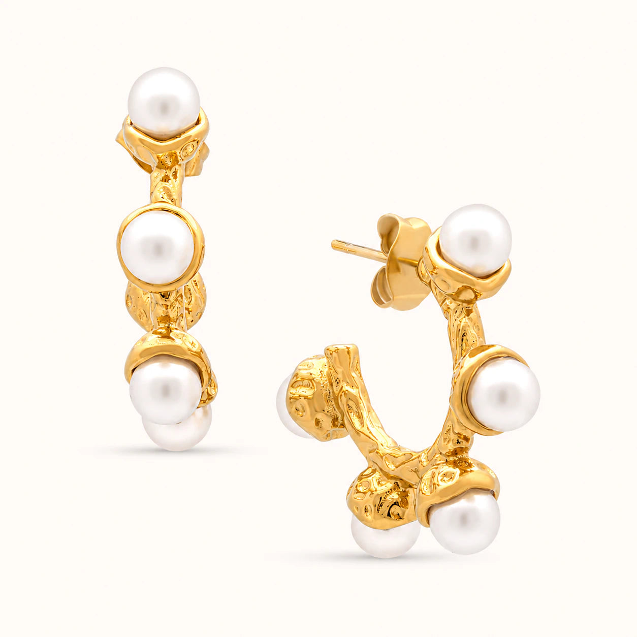 Gold earrings with pearl stones on a white background